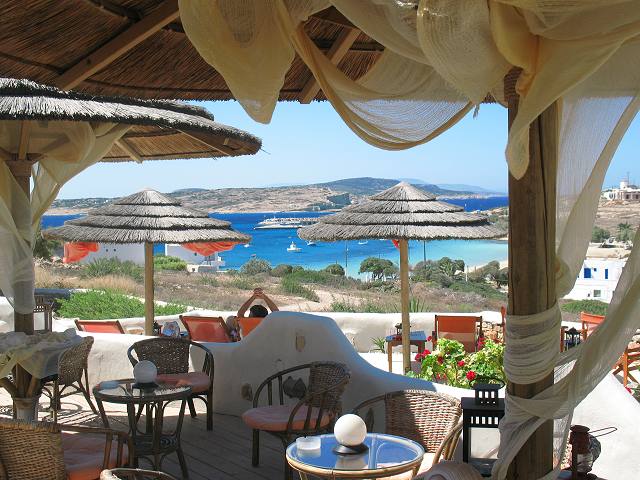 Shaded café terrace with straw parasols and sea views